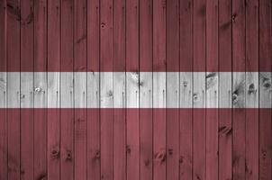 Lettland Flagge abgebildet im hell Farbe Farben auf alt hölzern Mauer. texturiert Banner auf Rau Hintergrund foto