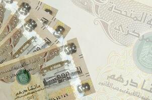 200 VAE-Dirham-Scheine liegen im Stapel auf dem Hintergrund einer großen halbtransparenten Banknote. abstrakter betriebswirtschaftlicher hintergrund foto