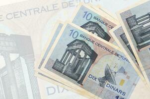 10 tunesische Dinar-Scheine liegen im Stapel auf dem Hintergrund einer großen halbtransparenten Banknote. abstrakte Darstellung der Landeswährung foto