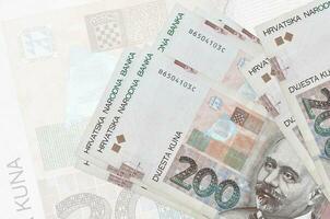 200 kroatische Kuna-Scheine liegen im Stapel auf dem Hintergrund einer großen halbtransparenten Banknote. abstrakte Darstellung der Landeswährung foto