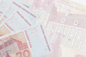 20 kroatische Kuna-Scheine liegen im Stapel auf dem Hintergrund einer großen halbtransparenten Banknote. abstrakter betriebswirtschaftlicher hintergrund foto