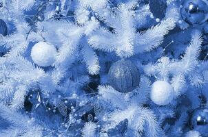 dekorieren Weihnachten Baum schließen hoch. Dekoration Birne, Weiß Tanne Baum, golden Weihnachten Spielzeuge und Beleuchtung. verwenden zum Weihnachten und Neu Jahre Feier Hintergrund. Phantom klassisch Blau Farbe foto