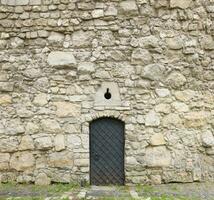 textur der mittelalterlichen steinmauer und der alten metalltür foto