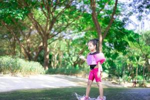 Kleines asiatisches Mädchen mit aufblasbaren Ärmeln, das im Urlaub Wasser im Naturwasser spielt foto