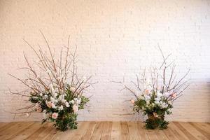 Dekorationen von Zweigen mit schönen rosa und weißen Blumen im Korb vor dem Hintergrund einer weißen Backsteinmauer foto