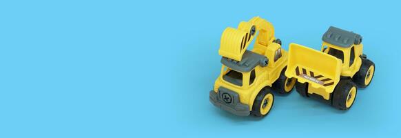 Gelb Plastik LKW und Bulldozer Spielzeug isoliert auf Blau Hintergrund mit Kopieren Raum zum Text oder Banner foto
