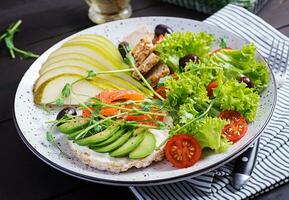 gesund Frühstück. Sandwiches mit Sahne Käse, Lachs, Avocado und Scheibe Birne auf Platte. foto