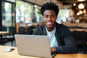 Porträt von heiter schwarz männlich Schüler Lernen online im Kaffee Geschäft, jung afrikanisch amerikanisch Mann Studien mit Laptop im Cafe, tun Hausaufgaben foto