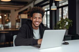 Porträt von heiter schwarz männlich Schüler Lernen online im Kaffee Geschäft, jung afrikanisch amerikanisch Mann Studien mit Laptop im Cafe, tun Hausaufgaben foto