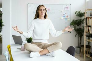 jung Geschäftsfrau üben Yoga während Sitzung auf Tabelle beim Büro foto