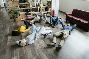 Geschäft Mannschaft Lügen auf das Fußboden umgeben durch Unterlagen im Dachgeschoss Büro foto
