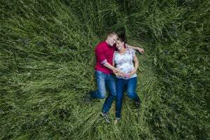 schwanger Frau und Mann halten Baby Bauch, Lügen auf Wiese foto