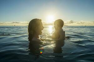 Französisch Polynesien, Tahiti, Papeete, Frau spielen mit ihr wenig Baby im ein Unendlichkeit Schwimmbad beim Sonnenuntergang foto