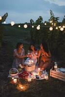 freunde haben ein Picknick im ein Weinberg auf Sommer- Nacht foto