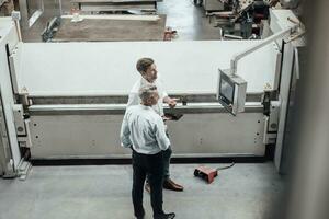 reifen männlich Ingenieure diskutieren Über Herstellung Ausrüstung im Fabrik foto