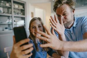 spielerisch Vater und Tochter nehmen ein Selfie beim Zuhause foto