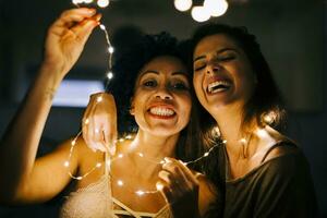 Nahansicht von heiter weiblich freunde halten beleuchtet Zeichenfolge Beleuchtung beim Zuhause foto