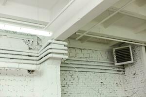 Backstein Mauer Textur, Weiß Backstein Mauer und elektrisch Hitze Konverter im ein Ecke. Grunge Dachgeschoss Innere Design foto