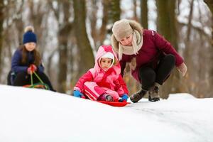 schön wenig Mädchen tragen Jacke und gestrickt Hut spielen im ein schneebedeckt Winter Park. Familie Ferien mit Kind im Berge foto