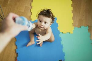 Vaters Hand geben Baby Junge ein Flasche von Wasser foto