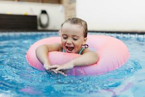 Porträt von wenig Mädchen mit schwebend Reifen im Schwimmbad foto