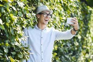 glücklich jung Mann nehmen Selfie im ein Hecke foto