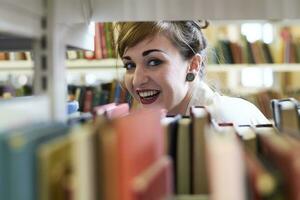 weiblich Schüler lesen Buch im ein Öffentlichkeit Bibliothek foto