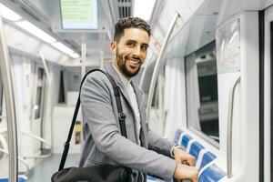 Porträt von lächelnd jung Geschäftsmann mit Kopfhörer auf das U-Bahn foto