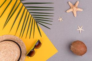 Strandaccessoires, Brille und Hut mit Muscheln und Seesternen auf farbigem Hintergrund. Sommer Hintergrund foto