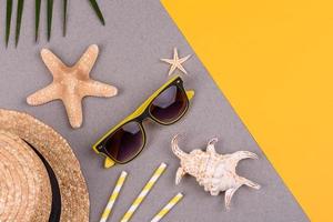 Strandaccessoires, Brille und Hut mit Muscheln und Seesternen auf farbigem Hintergrund. Sommer Hintergrund foto