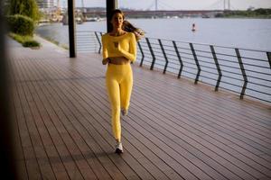 junge Frau beim Lauftraining an der Flusspromenade foto