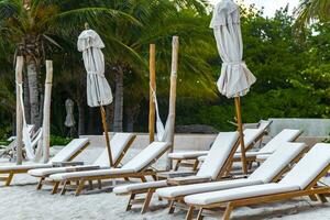 Palapa mit Stroh gedeckt Dächer Palmen Sonnenschirme Sonne Liegen Strand Resort Mexiko. foto