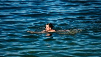 Ein junges Mädchen schwimmt im kristallklaren Wasser eines Bergsees. foto