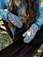 weiblich Hände im Wolle Handschuhe auf ein Bank im das Park. foto