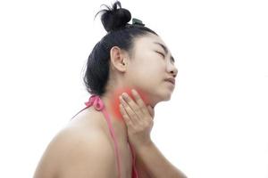 junge asiatische frau, die ihren hals berührt und auf weißem hintergrund schmerzen im hals verspürt foto