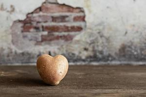 Herzförmige rote Kartoffel auf Vintage background.the Konzept der Landwirtschaft, Ernte, Vegetarismus. Valentinstag. quadratisches, hässliches Essen. foto