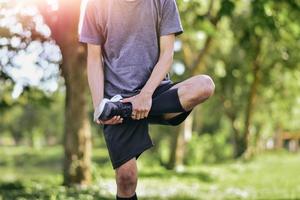 Mann, der seine Beinmuskeln vor dem Training ausdehnt, junge männliche Jogger-Athleten-Ausbildung foto