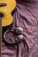 Kopfhörer und klassische Gitarre im Bett foto