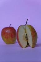 ein gespaltener Apfel mit rosa Hintergrund, ein perfektes Foto für eine Lebensmittelpeitsche