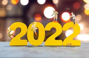 Miniaturmenschen klettern auf Holz mit der Nummer 2022 foto