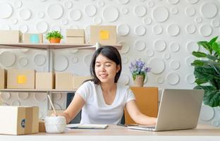 junge asiatische Frau Start-up-Kleinunternehmerin, die mit digitalem Tablet am Arbeitsplatz arbeitet - Online-Verkauf, E-Commerce, Versandkonzept