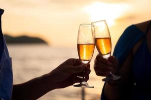 Hand hält ein Glas Wein trinken auf Sonnenuntergang Meer Hintergrund. foto