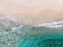 Luftaufnahme von klaren Meereswellen und weißen Sandstränden im Sommer.