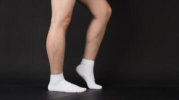 asiatisch männlich Beine tragen Weiß Socke ist isoliert auf schwarz Hintergrund foto