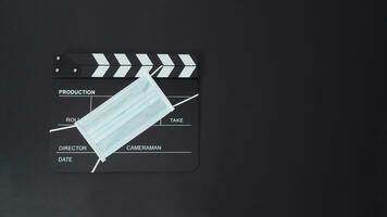 Klöppel Tafel oder Film Schiefer mit Gesicht Maske. es verwenden im Video Produktion und Kino Industrie auf schwarz Hintergrund. foto