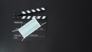 Klöppel Tafel oder Film Schiefer mit Gesicht Maske. es verwenden im Video Produktion und Kino Industrie auf schwarz Hintergrund. foto