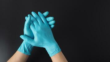 zwei Hand mit Blau Latex Handschuhe auf schwarz Hintergrund. foto