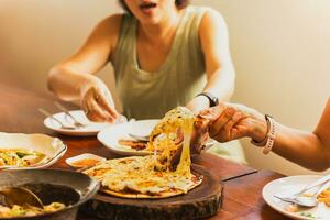 Frau Hände nehmen Scheiben von Pizza mit Freunde. foto