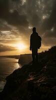 Silhouette von ein Person bewundern das Sonnenuntergang beim das Kante von ein Cliff foto