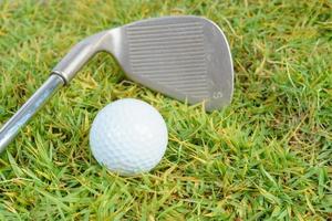 Golfschläger und Golfball auf grünem Grashintergrund